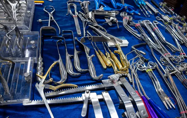 Tıbbi işlemlerde kullanılmak üzere masada kıskaçlar ve sökücüler de dahil olmak üzere cerrahi aletlerden oluşan bir seçim sunulmaktadır..