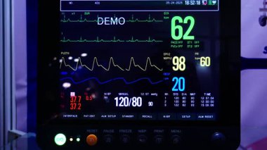 Sağlık uzmanları için ekranda oksijen, nabız ve diğer parametreleri gösteren bir kritik bakım izleme birimi gösterilmiştir..