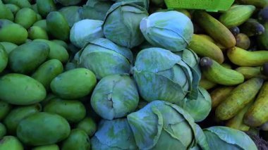 Lahana ve yeşil çiğ mangolar satışa sunuluyor, tazeliklerini sergiliyorlar..