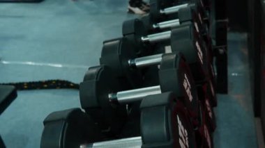 Çeşitli ağırlıklardan dambıllar spor salonundaki raflarda düzenli olarak spor meraklıları için kullanılabilir..