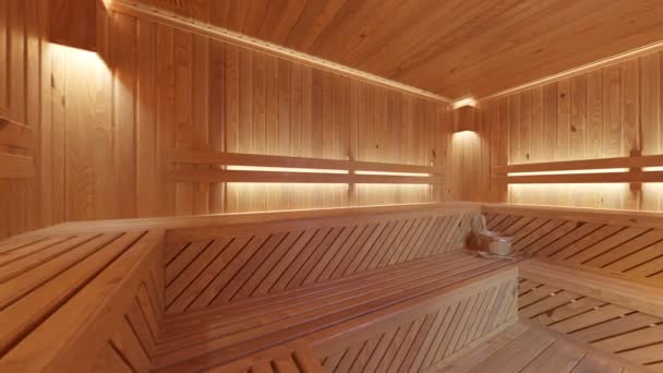 伝統的なアクセサリー付きの空のサウナのインテリア 大きな木製のフィンランド式サウナ リラクゼーションとクレンジングのためのスパルーム 暖かいライトによって照らされる快適な木の部屋 — ストック動画