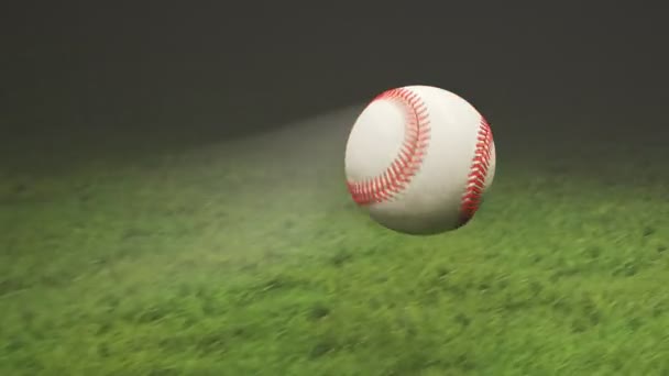 白色的皮革棒球在新割下来的体育场草地上缓慢地在空中飞舞 有运动模糊条纹的慢动作的无限运动 竞技场的聚光灯照亮田野 — 图库视频影像
