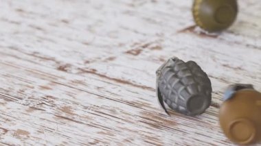 Tahta zeminde yuvarlanan farklı el bombaları. Kamera iki ananas bombasıyla kapanır. M26, MK2 ve el bombaları düz bir yüzeye fırlatıldı. Patlayıcılarla savaşa hazırlanıyor. 4KHD