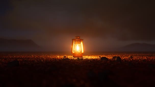 小さな小石に囲まれた砂漠の真ん中に立っている古いヴィンテージランプ 暗闇に希望を与える暖かい炎の光 旅行休憩する 背景にあるヒルズ カメラトラック — ストック動画