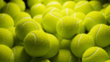 Muazzam miktarda sarı tenis topunun görüntüsü. Kusursuz döngü animasyonu. Siyah arka planda birçok profesyonel spor topu var. Sert ışık, koyu gölgeler. Spor malzemeleri. 4K HD 'yi hazırla.
