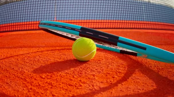 蓝色网球拍 球落在橙色的球场上 背景中的网络 相机倾斜了下来 运动器材 健康和积极的生活方式 在比赛的中间 — 图库视频影像