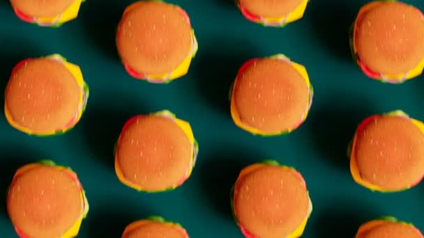 芝士汉堡无缝线动画 一排排好吃的快餐三明治在同一个方向上跳跃着 一起移动着 在绿色的背景上 排列着五彩斑斓的汉堡包 — 图库视频影像