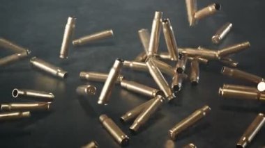 Yere düşen boş mermilerin canlandırması. Ateş açın. Karanlık arka planda silah mühimmatı. Tüfekten ateşlenen metal mermiler. Tabanca atışı. Ordu, polis ya da av mühimmatı. Savaş, çekim, suç