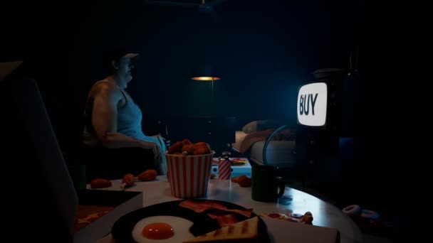 Fat Guy Seating Dark Room Staring Surrounded Tones Food Snacks — Stock Video
