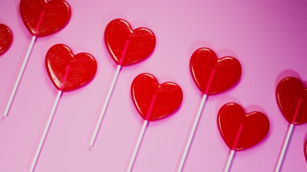 无缝线动画的红色心形棒棒糖 一套用木棍做的甜甜食 爱情的象征 粉色背景的甜糖果 甜蜜浪漫的情人节礼物 — 图库视频影像