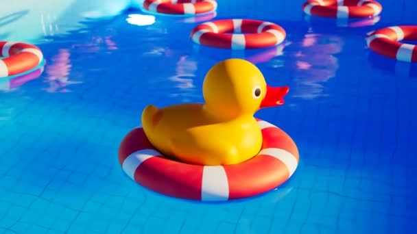 プールに浮かぶライフ リングのゴム製アヒル カメラダウン 水の中のかわいい黄色いおもちゃ バックグラウンドにサンベッドと傘のあるリラクゼーションゾーン 喜びと陽気な雰囲気 — ストック動画