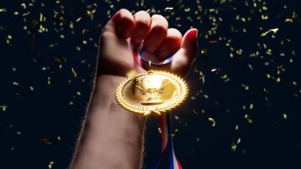 举起一只手拿着闪亮的金牌 冠军和一等奖 冠军的体育奖 赢得了比赛 荣耀的时刻 最伟大的成就Confetti案 — 图库视频影像