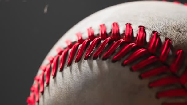 棒球赛令人惊叹的动画 一个孤立的白色皮革球与红色似乎在黑暗的背景 摄像机把球放大了 大联盟棒球 美国的运动 美丽柔和温暖的光线 — 图库视频影像