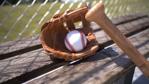 棒球手套 球和球棒在木制长椅上 棒球配件 运动服 摄像机在周围打转美丽的温暖的光 游戏中的制动器概念 大联盟棒球 美国体育 — 图库视频影像