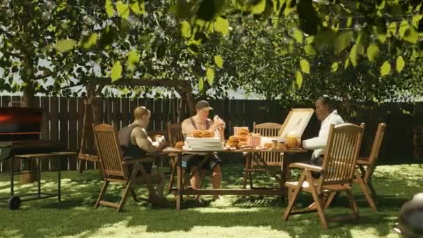 Bahçe Partisi Arkadaş Yemek Dolu Masanın Etrafında Sosisli Hamburger Yiyorlar — Stok video