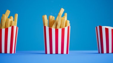 Kusursuz kıvrımlı 3D animasyon ve mavi arka planda patates kızartması. Çıtır çıtır tuzlu atıştırmalıklar beyaz ve kırmızı çizgili karton kutulara düşüyor. Fast food hazırlığı. Lezzetli mezeler..