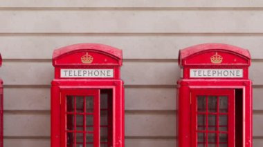 Duvarda İngiliz kırmızı telefon kulübeleri olan kusursuz bir döngü animasyonu. Geleneksel Londra ve İngiliz sembolü. Sokaktaki eski haberleşme kulübeleri. Antika telefon. Telefona bak..