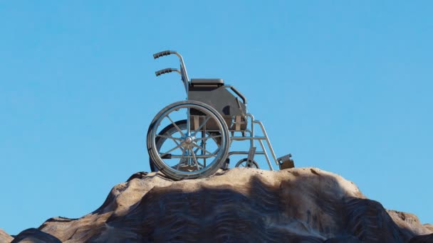 山の頂上にある空の車椅子 バックグラウンドに青い空の岩のピーク 健康上の困難を克服する概念 脚の機能を復元する 障害者 障害者 トラベル インバリッド — ストック動画