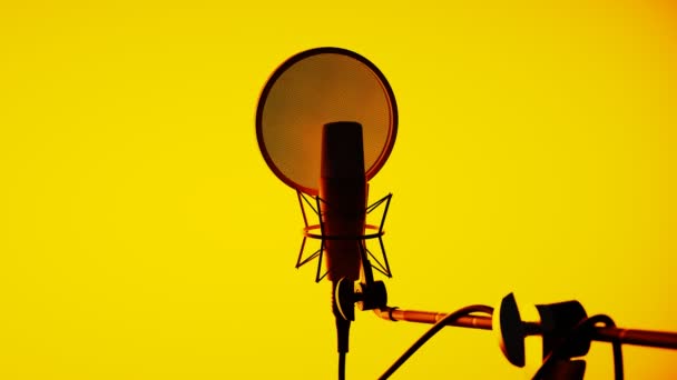 带弹出滤波器和防震装置的录音室冷凝器话筒录音 关闭音箱中的话筒 音响设备 米克五彩缤纷的灯光黄色背景 — 图库视频影像