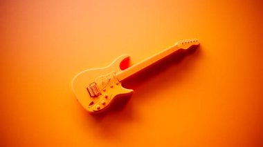 Altı telli elektro gitar. Dört pikaplı bir müzik aleti. Turuncu arka planda stüdyo ışığı olan zarif bir müzik aleti çekimi. Rock, heavy metal, blues, pop, rhythm, lead, gitar.