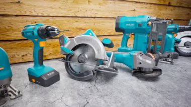 Ahşap arka planda endüstriyel aletler. Elektrikli cihazlar. Zanaatkar atölyesi. Profesyonel elektrikli aletler. Gerekli ekipmanlar. Dairesel testere, kablosuz matkap, çim biçme makinesi, testere, döner çekiç. Döngü
