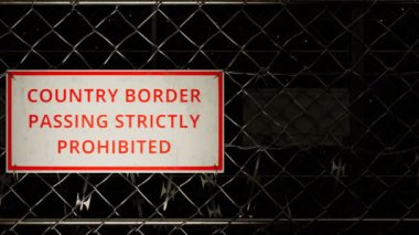 İki ülke arasındaki sınır çiti. Yasadışı göçmen göçmenlerin korunması. Sınır bölgesi. Sivri uçlu sivri uçlu metal dikenli tellerden yapılmış kalıcı bir barikat. Gece manzarası