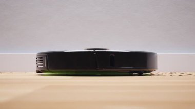 Akıllı robot enkazı temizler. Dönen fırçalar tozu temizler ve ahşap zemini temizler. Uzaktan kumandalı. Programlanabilir temizlik rutinleri. Kendi kendine gidiyor. Nesneler ve engeller tanımlanıyor. Yakın plan..