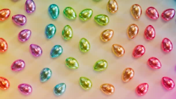Блискучі Металеві Загорнуті Плівку Шоколадні Яйця Розташовані Муті Кольоровій Веселковій — стокове відео