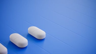 Mavi arka planda beyaz haplar. İlaç, eczane ya da sağlık konuları için mükemmel bir geçmiş. Vitaminler ve düzgün işler için takviyeler. Kusursuz döngü canlandırması.
