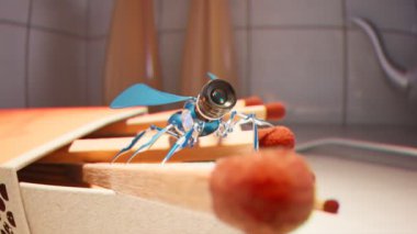 Son derece küçük mavi röntgenci robot kibrit kutusunun üzerinde dikilip sakinleri izliyor. Kamera lensli mikro böcek. Kamera özel bir şeye odaklanıyor. Ayrıntılı makro çekim.