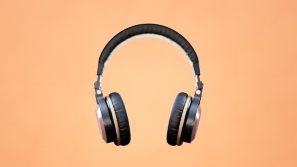 Müziği Açık Olan Kablosuz Kulaklıklar Turuncu Arka Planda Ritimle Hareket — Stok video