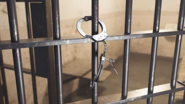 手錠から抜け出す 1つの側面は鋼鉄刑務所の棒でロックされ 2番目はキーを使用して開きます 囚人は逃げ出した キーがゆっくりと動いています バックグラウンドの刑務所のセル Hdレンダリング — ストック動画