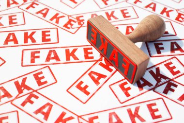 Belgede sahte damgalı çoklu kırmızı metinler olan tahta damga. Sahte evraklar kontrol edildi. Dolandırıcılık, sahte haber evrakları aldatmacası. Özgünlüğün doğrulanması.