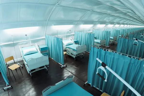 Rows of hospital beds separated by curtains in a field hospital. Empty beds waiting for patients during a pandemic. White tent of a military hospital. covid-19
