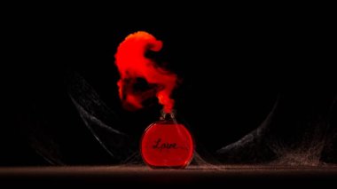 Cam bir şişede kırmızı bir aşk iksiri. Örümcek ağlarıyla kaplı. Sihirli kırmızı dumanla kaçıyorlar ve kalp şekli oluşturuyorlar. Sahne karanlık ve tozlu bir odada geçiyor..