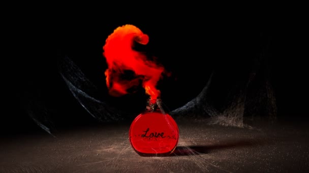 一种红色爱情药水 装在一个玻璃瓶里 上面布满了蜘蛛网 散发着神奇的红色烟雾 形成了心脏的形状 场景发生在一间灰蒙蒙的房间里 — 图库视频影像