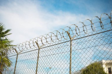Yürüyüşe çıkmış bir mahkumun perspektifinden dışarıdaki hapishane çitleri. Özgürlüğün sınırı. Çit uzun ve heybetli, tepesinde dikenli teller var ve gözün görebildiği kadar uzanıyor.