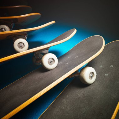 Stüdyo ışıkları altında üst üste binen kaykaylar. Altında parlak mavi bir kat var. Modern gençlik yaşam tarzı ve aşırı hobi. Kaykay dükkanı aksesuarı. Ekstrem sporlar.