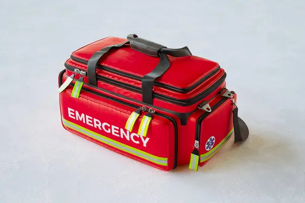A professional red emergency first aid bag in simple studio light. Paramedic fast response in case of life in danger. Doctors\' kits equipped with everything needed to help patients. White background
