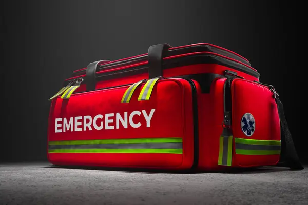 A professional red emergency first aid bag on in studio spotlight. Paramedic fast response in case of life in danger. Doctors kit equipped with everything needed for helping patients. Saving lives.