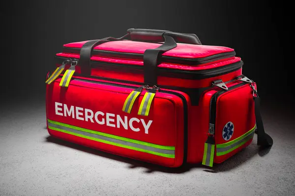 A professional red emergency first aid bag on in studio spotlight. Paramedic fast response in case of life in danger. Doctors kit equipped with everything needed for helping patients. Saving lives.