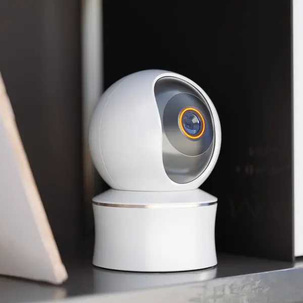 White spherical smart camera watching and recording from an office shelf. A sophisticated piece of wireless technology equipment working flawlessly. Voyeur machine gathering secret information.