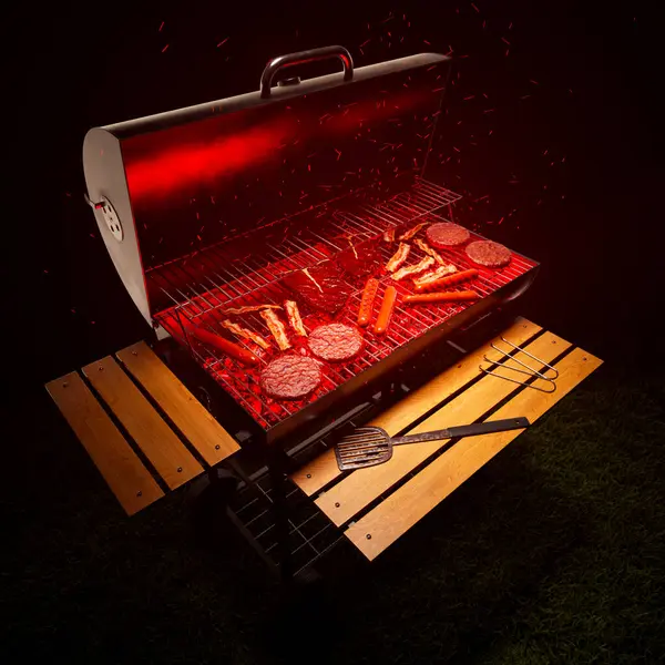 Grilling at the garden. Traditional American barbeque. Crispy steaks, sausages, bacon and burgers. Delicious meat. Preparing a tasty meal. Grilled meat. Grill with red hot charcoal. Dark background.