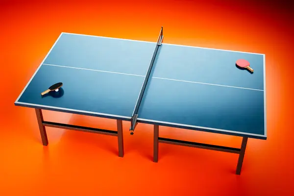 A professional setup of a blue table tennis table standing in an empty room with vibrant red flooring. Rackets and a ball are placed on the table, ready for players to start a game