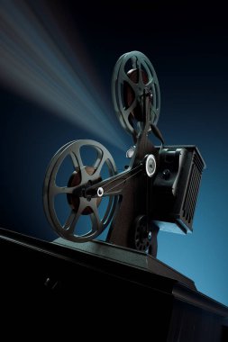 Eski moda bir film projektörünün canlandırıcı bir sahnesi. Parlak ışığı karanlık arka planı delip geçmiş sinematik zamanların özünü ve analog teknolojinin çekiciliğini yakalıyor..