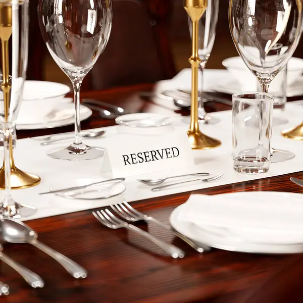 洗練されたカトラリー クリスタルグラスウェア エレガントな Reserved サインを備えた細かく配置されたダイニングテーブルは 排他的な美食イベントを示しています — ストック写真