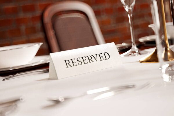 An intricately arranged table with a "RESERVED" placard at a high-end restaurant, showcasing a luxurious dining atmosphere with pristine tableware and inviting ambiance for a special event or dinner.
