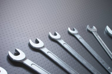 Bu resim düzgün organize edilmiş metal anahtar setini, mekanik çalışmaları sembolize eden, tamir ve mühendislik için elle işletilen araçların özünü sembolize eden, dokulu noktalı bir arka planda sergiliyor..