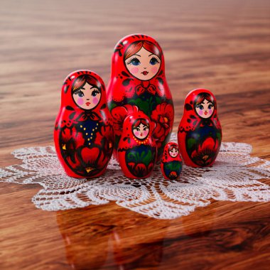 Canlı bir geleneksel Rus Matrioshka dizisi, zengin kültür mirasını gözler önüne seren dantelli ahşap bir masada karmaşık çiçek desenleriyle süslenmiş..