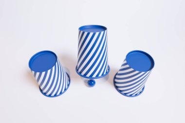 An aesthetically pleasing arrangement of three blue and white striped ceramic cups overturned with a coordinating ball, set against a stark white background to enhance visual impact. clipart